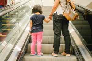 Mom and daughter ascend escalator